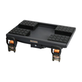 A black heavy-duty equipment with four cushioned support pads on top and two orange ratchet straps with hooks on the sides for securing loads